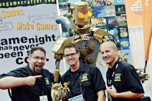The Game Crafter founders JT Smith, Tavis Parker and Jamie Vrbsky posing with a large robot